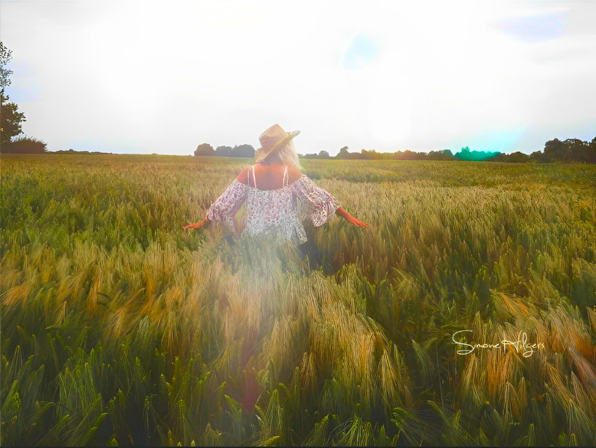Eine Frau sitzt auf einem Berg und schaut in die Ferne in einen Wald der mit Nebel umhüllt ist.
