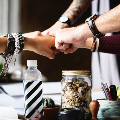 5 Menschen stoßen sich auf dem Tisch gemeinsam die Fäuste